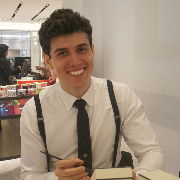 Danny Weiner wearing a tie and suspenders smiling at a desk